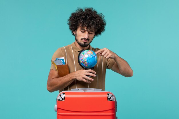 Hombre de vacaciones sosteniendo un pequeño globo en azul