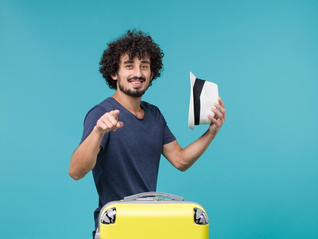 hombre de vacaciones sosteniendo sombrero en azul