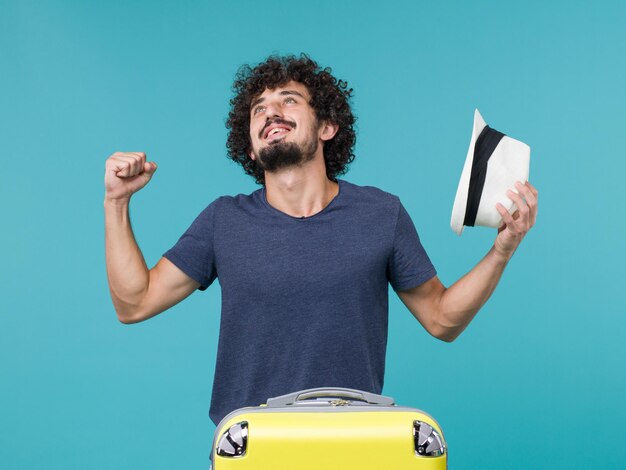 hombre de vacaciones sosteniendo su sombrero en azul