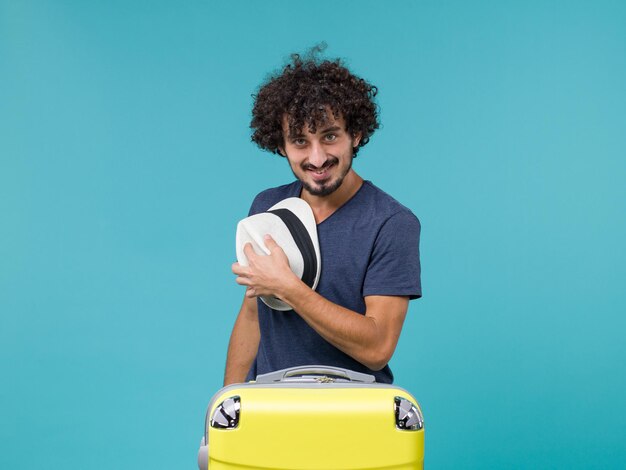 Foto gratuita hombre de vacaciones sosteniendo su sombrero en azul