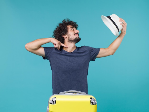 Foto gratuita hombre de vacaciones sosteniendo su sombrero en azul