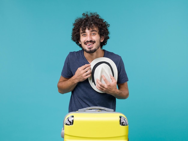 Foto gratuita hombre de vacaciones sosteniendo su sombrero en azul