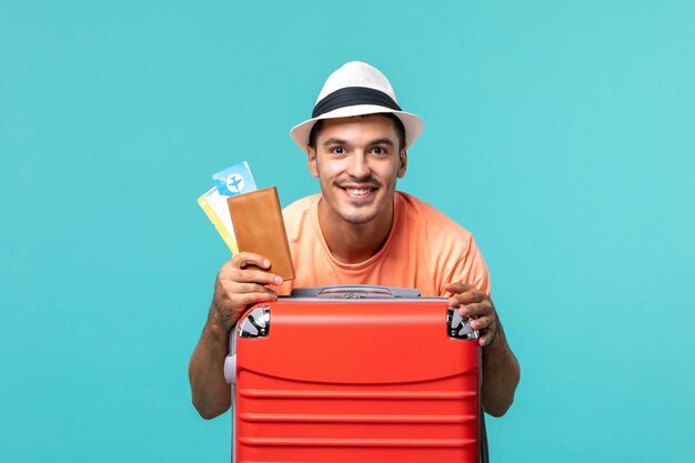 Hombre de vacaciones sosteniendo sus boletos y sonriendo en azul