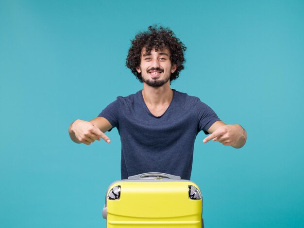 Hombre de vacaciones con su maleta amarilla sobre azul