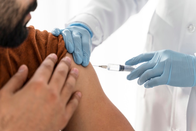 Foto gratuita el hombre está vacunando por un médico de cerca