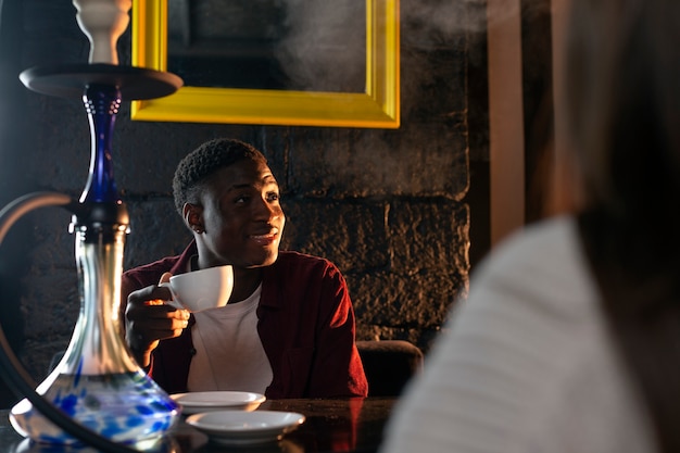 Hombre vaping de una pipa de agua en un bar