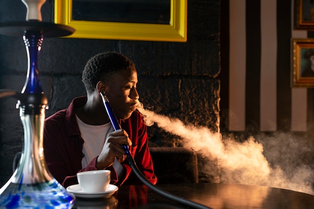 Hombre vaping de una pipa de agua en un bar