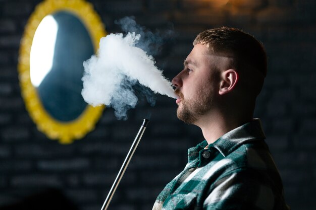 Hombre vaping de una pipa de agua en un bar