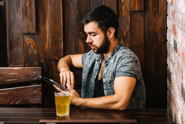 Hombre con vaso de cerveza con tableta digital