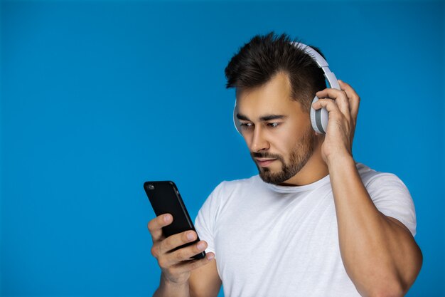 El hombre ve algo en el teléfono y escucha con los auriculares.