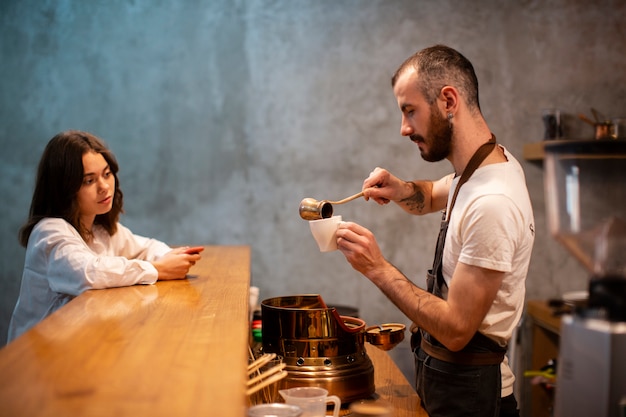 Hombre vertiendo café en taza para esperar al cliente