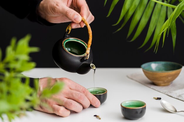 Hombre vertiendo té en la taza de té