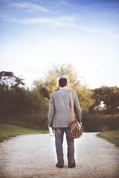 Foto gratuita hombre vestido con abrigo gris de pie cerca de la carretera durante el día