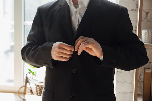 Hombre vestido con chaqueta negra. Cerca de manos masculinas caucásicas. Concepto de negocio, finanzas, trabajo, compras en línea o ventas.