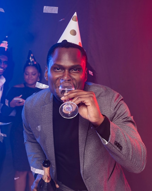 Hombre vestido con gorro de fiesta y bebiendo champán
