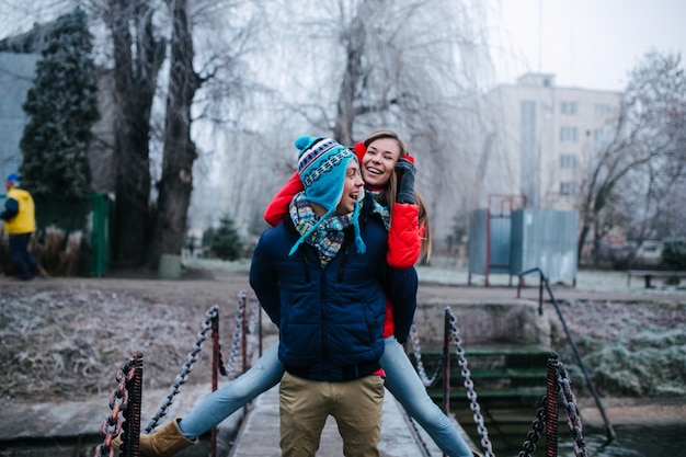 Hombre vestido de invierno con su novia en la espalda