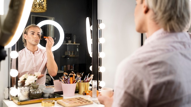 Foto gratuita hombre vestido con maquillaje cantar un pincel en su rostro