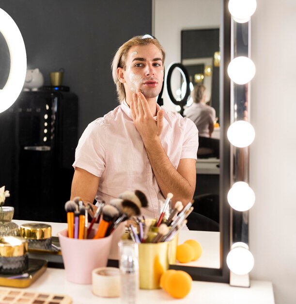 Hombre vestido con maquillaje con crema facial