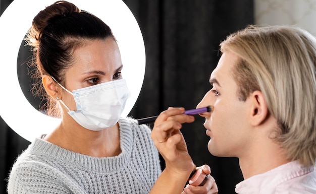 Hombre vestido con maquillaje y mujer con máscara