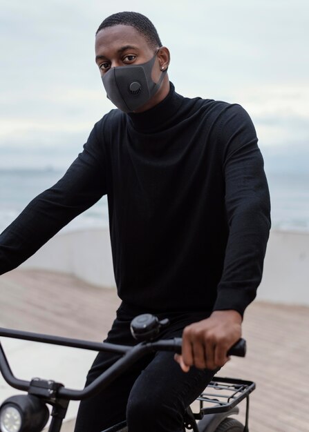 Hombre vestido con máscara facial y montando su bicicleta