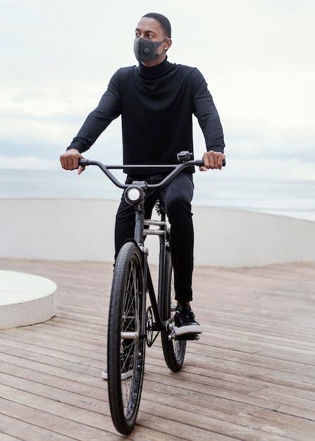 Hombre vestido con máscara médica y montando su bicicleta