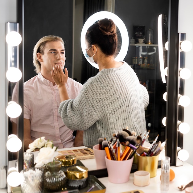 Hombre vestido con pinceles de maquillaje y maquillaje