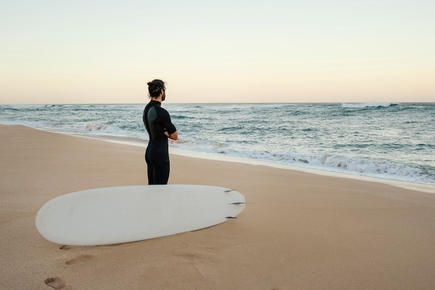 Hombre vestido con ropa de surfista viendo el amanecer