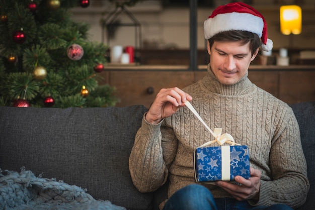 Hombre vestido con suéter abriendo regalo