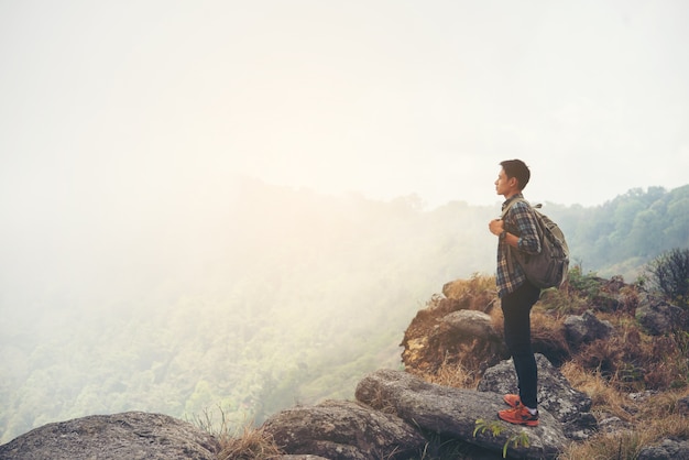 Hombre viajero con mochila en la cima de la montaña. Concepto de estilo de vida de viaje.