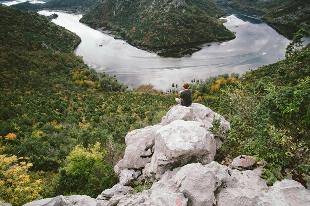 Hombre viajero sentado en la montaña y el enorme concepto de libertad