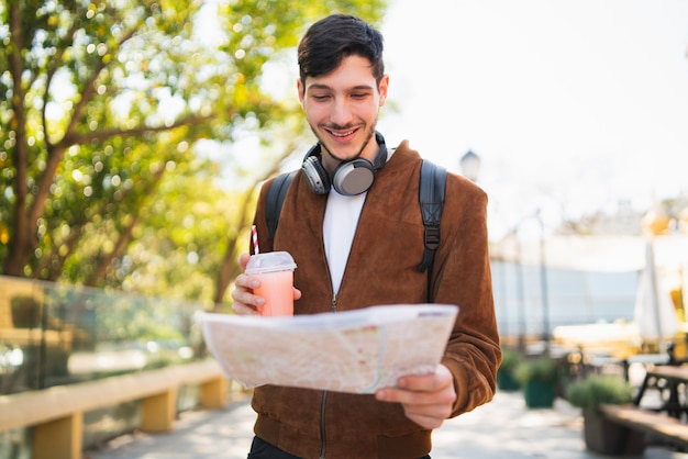 Hombre viajero sosteniendo un mapa y buscando direcciones.