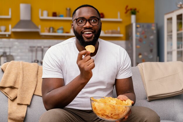 Hombre viendo la televisión y comiendo patatas fritas