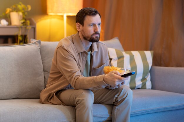 Hombre viendo la televisión y comiendo patatas fritas