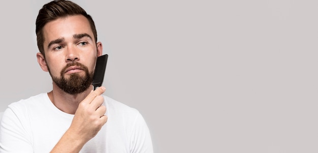 Foto gratuita hombre de vista frontal cepillándose la barba con espacio de copia