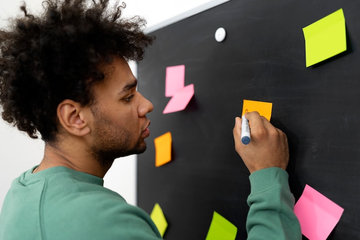 Foto gratuito hombre de vista lateral escribiendo en post-it