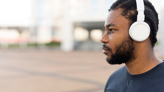 Foto gratuita hombre de vista lateral escuchando música a través de auriculares con espacio de copia