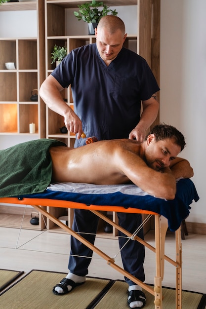 Foto gratuita el hombre de la vista lateral recibiendo un masaje profesional