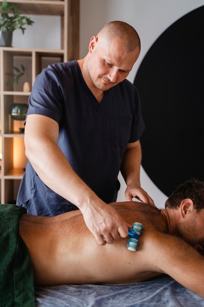 Foto gratuita el hombre de la vista lateral recibiendo un masaje profesional