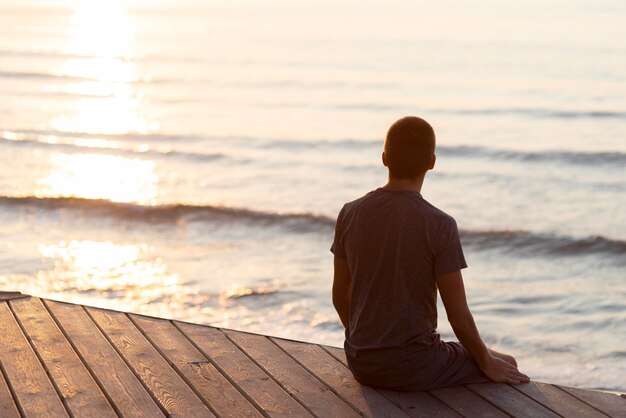 Hombre de vista posterior relajándose en la playa exterior con espacio de copia