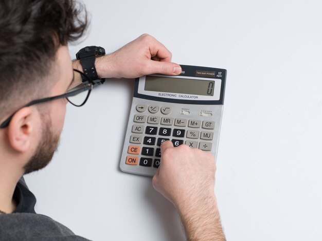 Un hombre de la vista superior con calculadora en el escritorio blanco