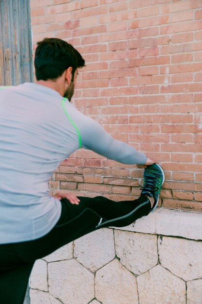 Hombre de vista trasera haciendo ejercicio junto a la pared