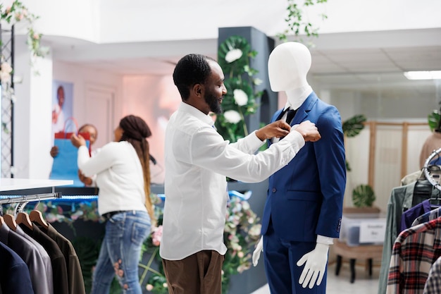 Hombre vistiendo maniquí en traje formal en tienda de ropa