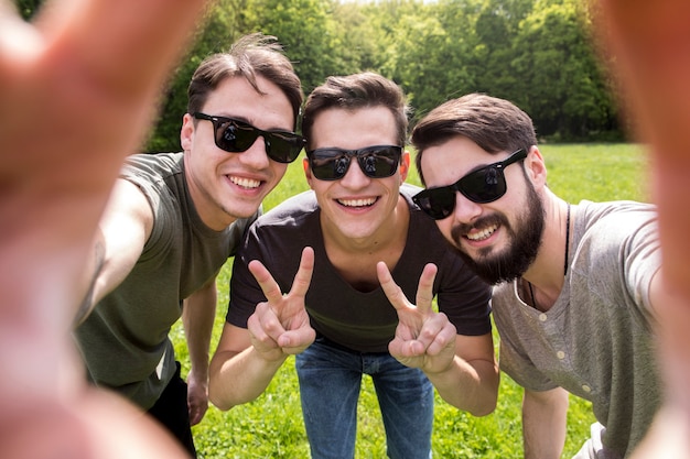 Foto gratuita hombres adultos en gafas de sol tomando foto en smartphone
