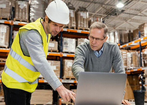 Hombres en almacén trabajando en equipo portátil