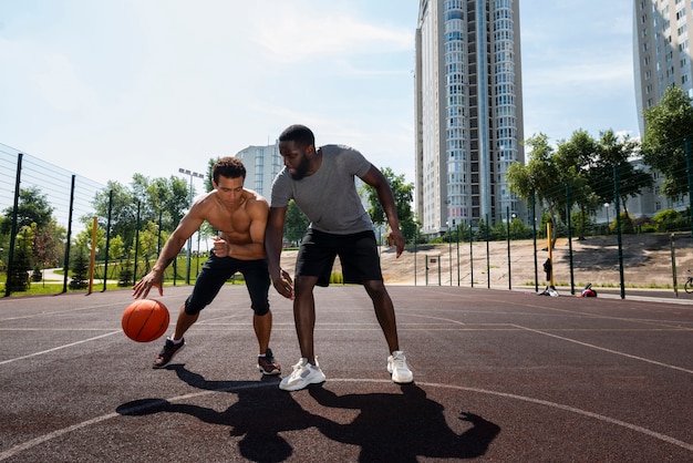 Hombres altos jugando en baloncesto urbano