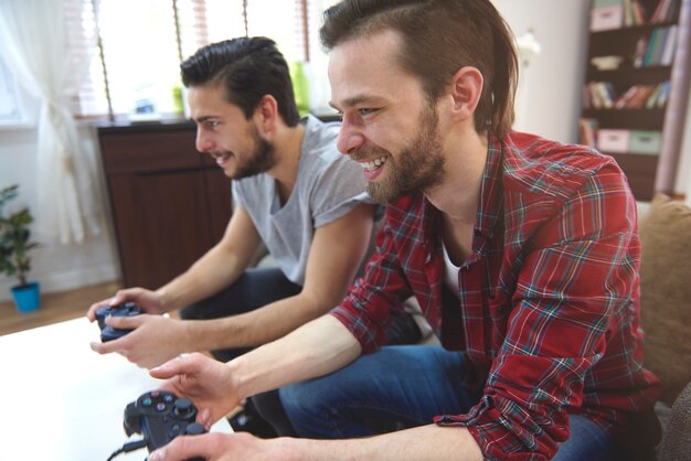Hombres cariñosos jugando playstation en la sala de estar