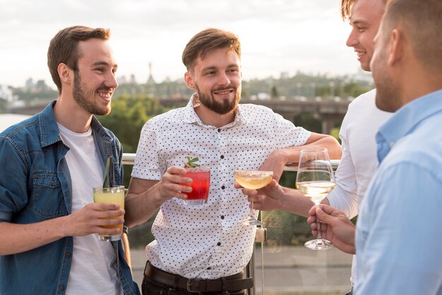 Hombres con copas en una fiesta en la terraza.