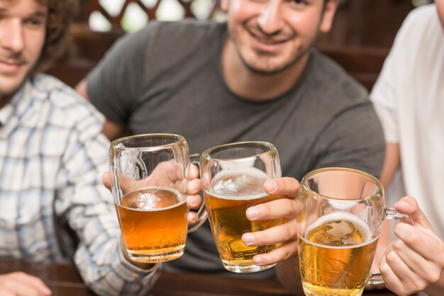 Hombres de cosecha que tintinean tazas en la barra