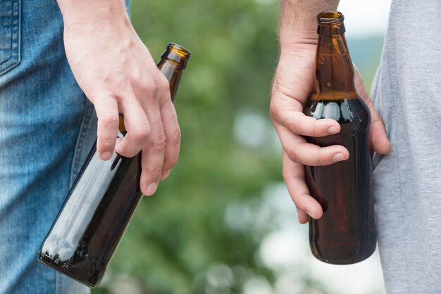 Hombres de cultivos relajantes con cerveza en la naturaleza