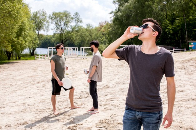 Hombres disfrutando de bebidas y sosteniendo frisbee.